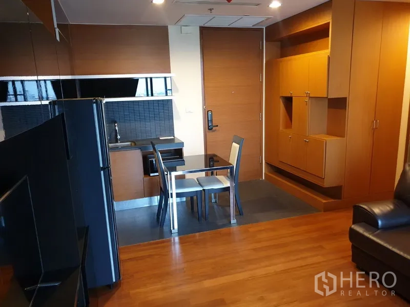 คอนโด ให้เช่าในKhlong Toei, Bangkok - มุมครัวแบบเปิด กระเบื้องผนังสีดำ โต๊ะกินข้าวกระจก และตู้บิวท์อินในคอนโด