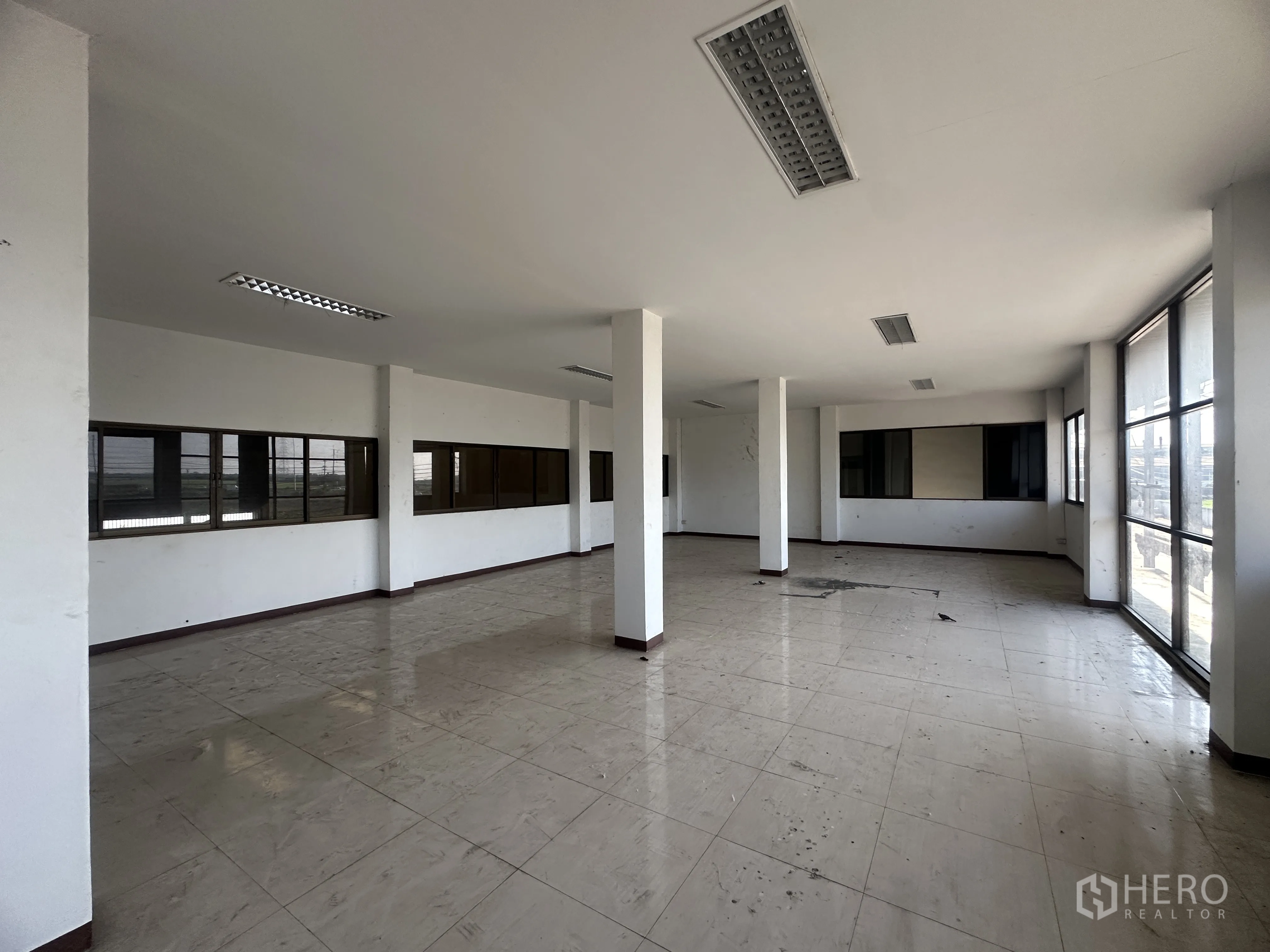 Factory for rent in Wang Noi, Phra Nakhon Si Ayutthaya - Open-plan office area with tiled flooring, columns, fluorescent lighting, and multiple windows.