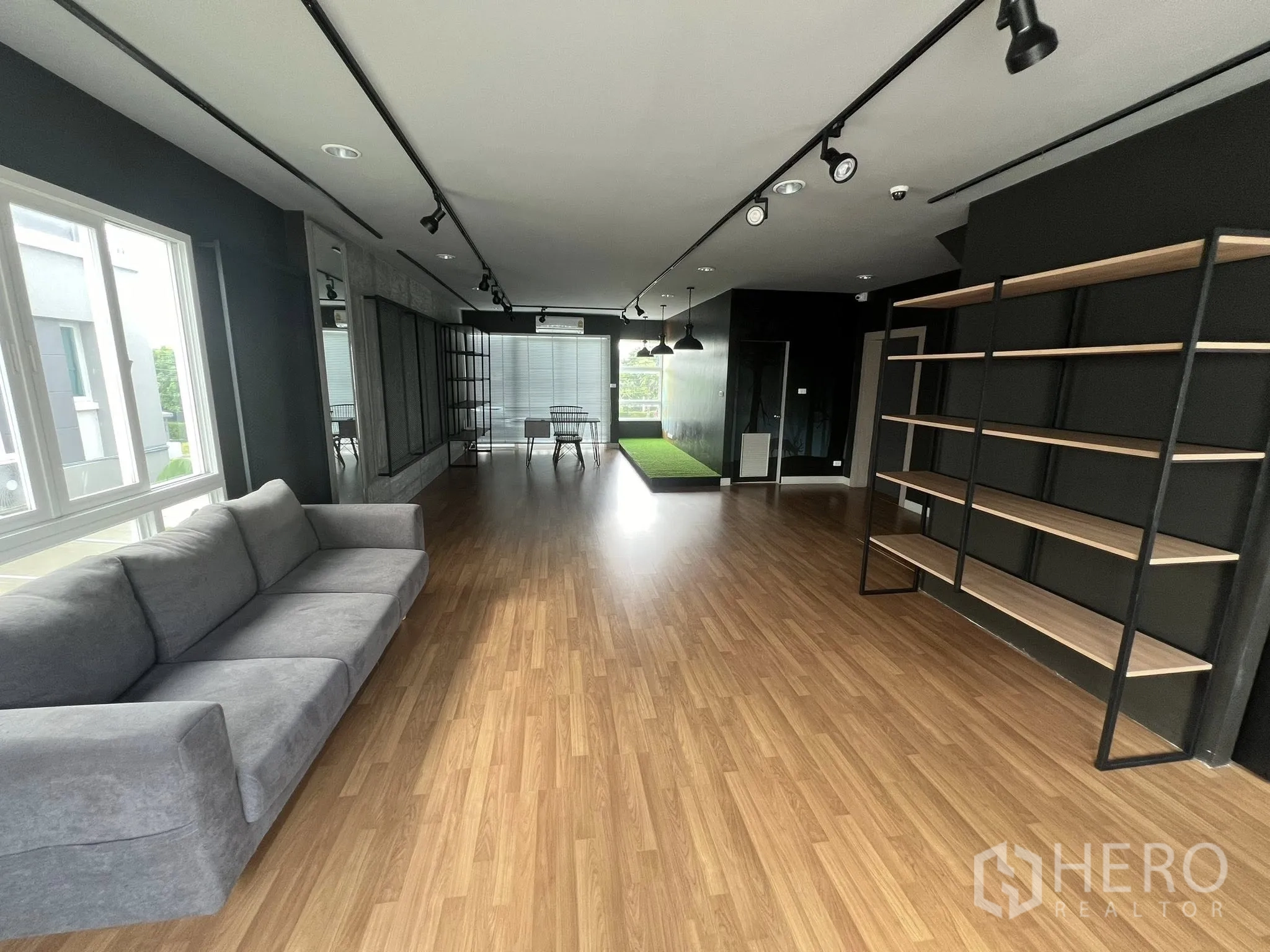 Detached House for rent or sale in Don Mueang, Bangkok - Large office lounge with sofa, shelving and spotlight tracks.