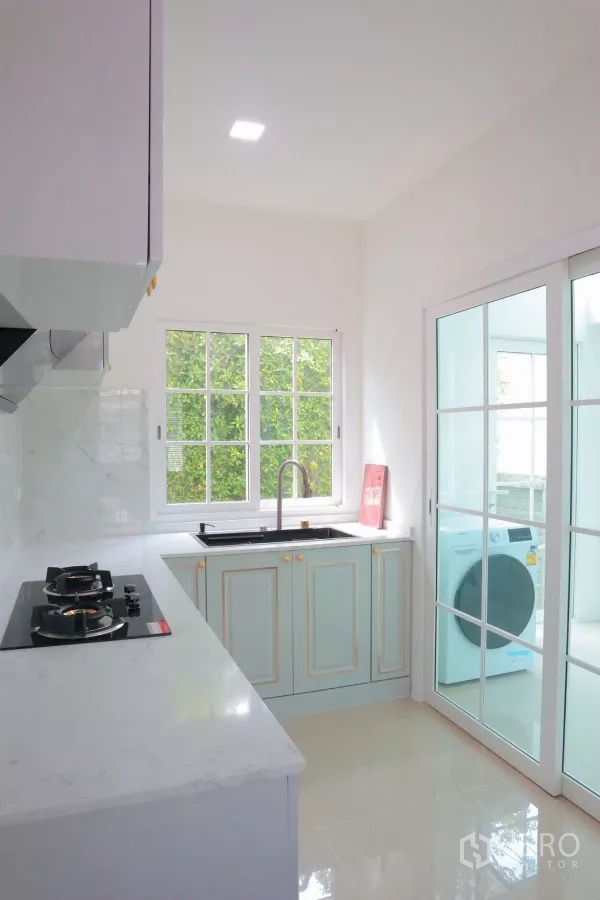 Detached House for rent in Bang Phli, Samut Prakan - Light kitchen with white countertops, gas hob and sliding door to laundry area.