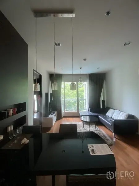 คอนโด ให้เช่าในPathum Wan, Bangkok - พื้นที่นั่งเล่นและรับประทานอาหารแบบเปิด โต๊ะสีดำ โซฟา ตู้ทีวี พื้นไม้ และประตูระเบียงมองวิวต้นไม้