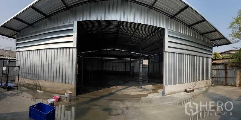 货栈 出租在Sai Mai, Bangkok - 金属外墙仓库正面，宽敞出入口与混凝土装卸场地。