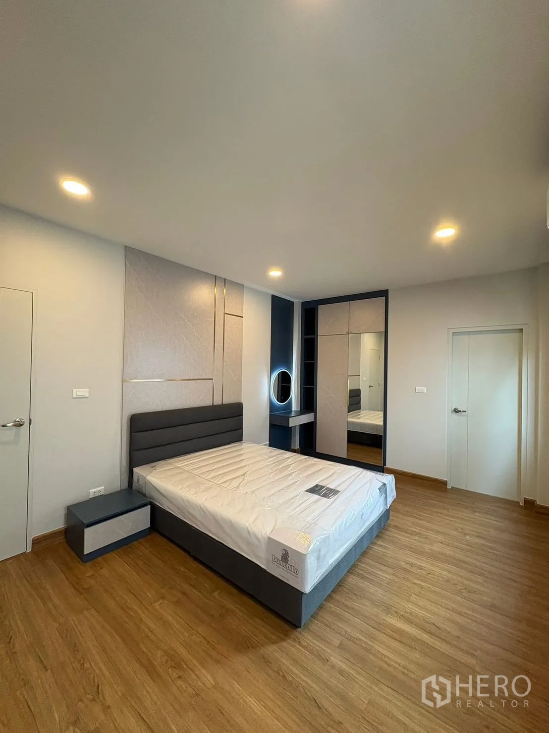 Detached House for rent in Bang Phli, Samut Prakan - Large bedroom with upholstered bed, accent wall, mirrored wardrobe and makeup nook.