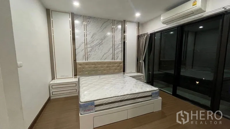 Detached House for rent or sale in Prawet, Bangkok - Bedroom with platform bed, large sliding glass doors and air conditioning.