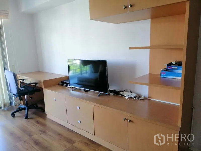 Condominium for rent in Watthana, Bangkok - Built-in TV cabinet with shelves, desk, and chair near the balcony.