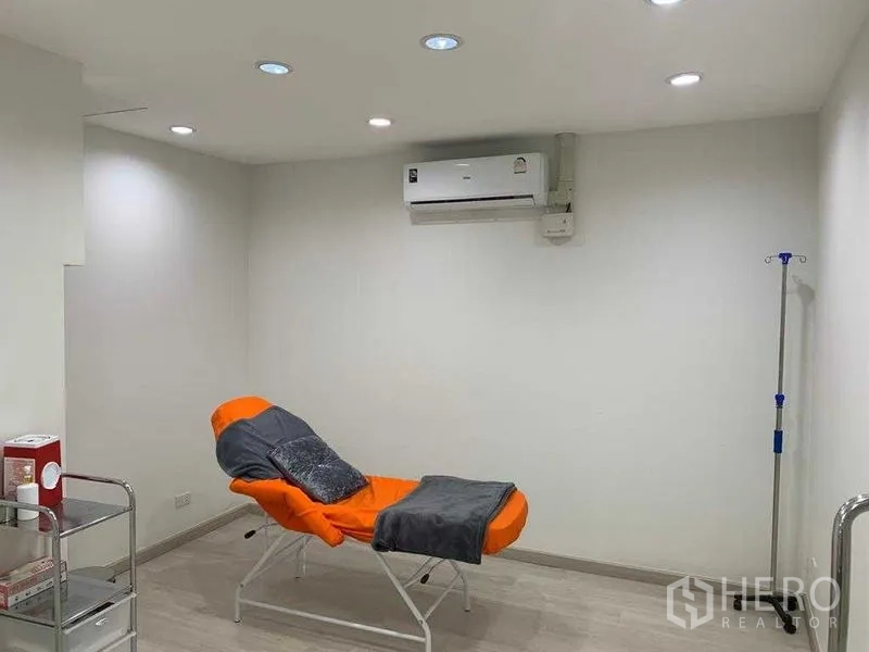 零售空间 出租在Pathum Wan, Bangkok - 简约治疗室，橙色躺椅、白色墙面与嵌灯顶。
