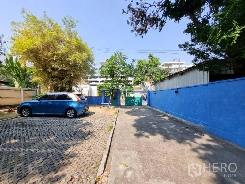 Detached House for rent in Khlong Toei, Bangkok - Driveway and on-site parking area behind a blue boundary wall.