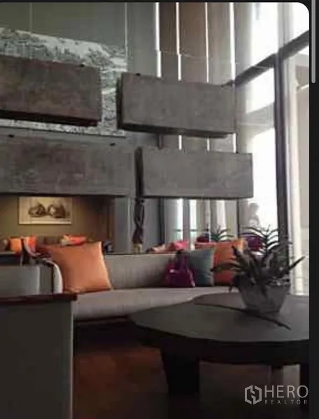 公寓 出租在Sathon, Bangkok - 挑高客厅，设有沙发、茶几、装饰板与落地窗，采光充足。