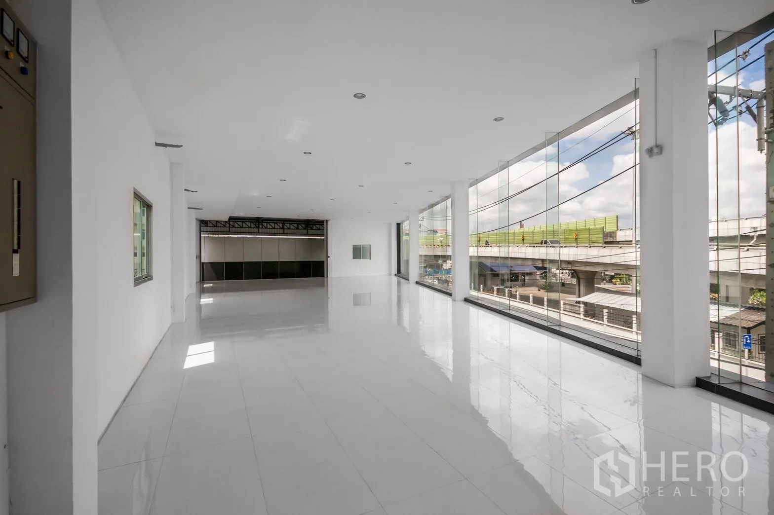 展厅 出租在Khan Na Yao, Bangkok - 楼上展示大厅，白色瓷砖地面与整面落地玻璃，俯瞰高架道路。