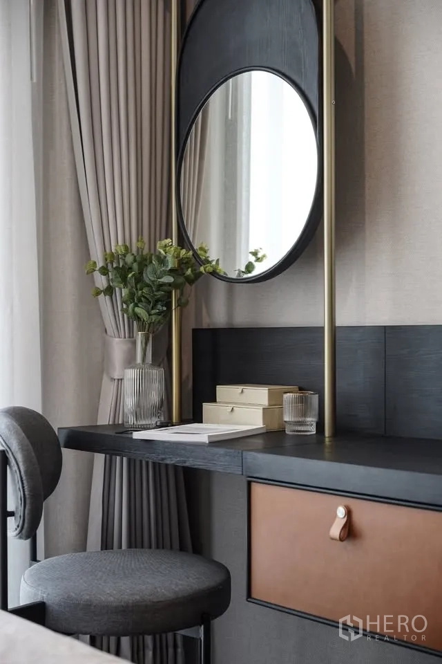 Condominium for rent in Watthana, Bangkok - Vanity workspace with round mirror, stool, and decorative plants by the window.