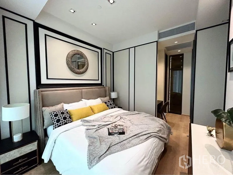 Condominium for rent in Pathum Wan, Bangkok - Master bedroom with decorative wall molding, gentle lighting and built-in wardrobe.
