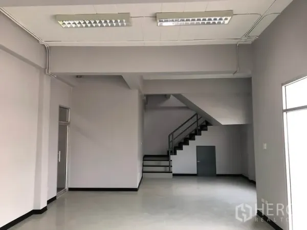 Factory for rent in Lat Lum Kaeo, Pathum Thani - Ground-floor office area with staircase to mezzanine and fluorescent lighting.