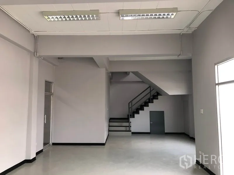 Factory for rent in Lat Lum Kaeo, Pathum Thani - Ground-floor office area with staircase to mezzanine and fluorescent lighting.