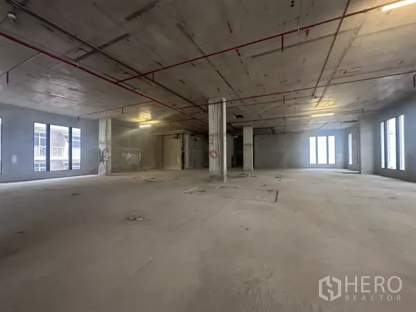 零售空间 出租在Watthana, Bangkok - 未完成的开放式商铺楼层，混凝土立柱、挑高天花与成排窗户。