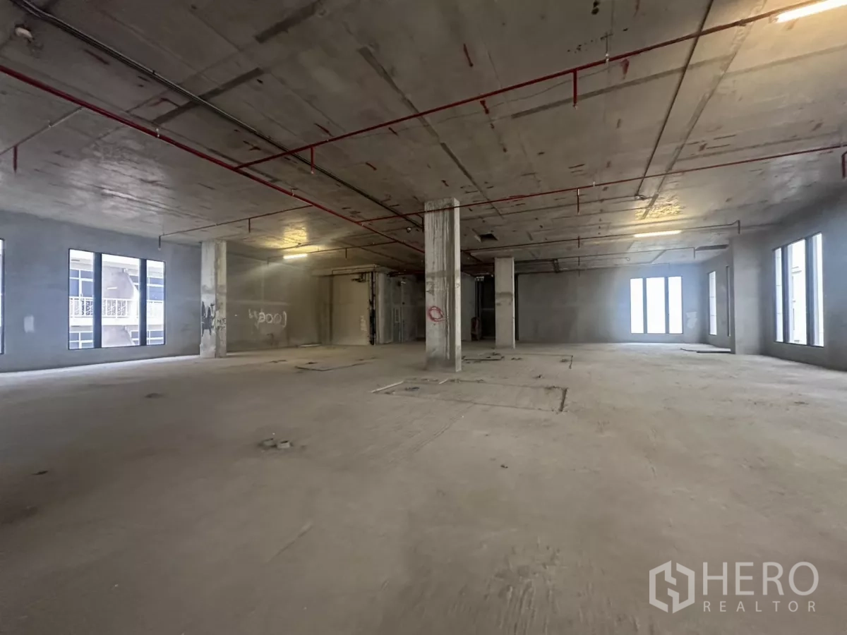 零售空间 出租在Watthana, Bangkok - 未完成的开放式商铺楼层，混凝土立柱、挑高天花与成排窗户。