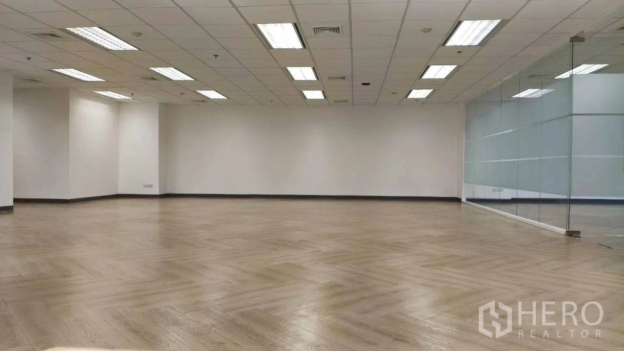 办公空间 for rent in Ratchathewi, Bangkok - 空置办公室，一侧整面玻璃墙，吊顶灯光与木地板