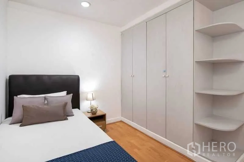 公寓 出租在Khlong Toei, Bangkok - 卧室配单人床、高柜与转角展示搁架。