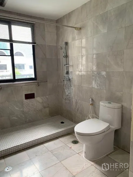 Townhouse for rent in Watthana, Bangkok - Marble-tiled bathroom with window, walk-in shower and modern toilet.