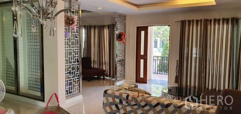 บ้าน ขายในKhan Na Yao, Bangkok - มุมห้องนั่งเล่นพร้อมฉากกั้นลายกระจกและประตูไม้เปิดสู่เฉลียง