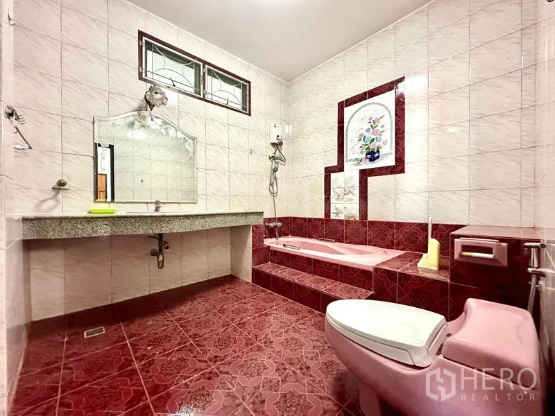 บ้าน ให้เช่าในTaling Chan, Bangkok - ห้องน้ำอ่างอาบน้ำแบบยกระดับสีชมพู ชักโครกเข้าชุด เคาน์เตอร์ยาว และผนังกระเบื้อง.