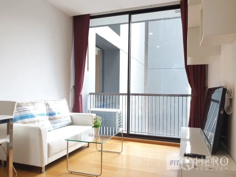 公寓 出租或出售在Bang Rak, Bangkok - 客厅配置白色沙发与玻璃茶几，落地移门通往阳台。