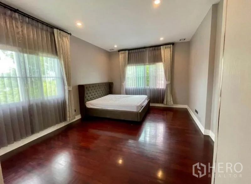 Detached House for rent in Bang Phli, Samut Prakan - Large bedroom with wood floors, sheer curtains and ample space.