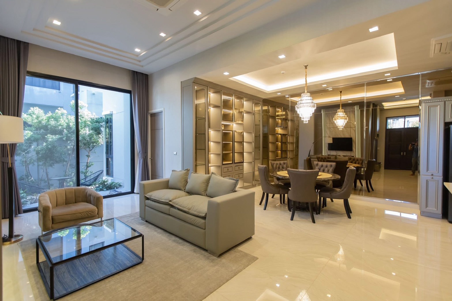 独立式住宅 出租在Lat Phrao, Bangkok - 宽敞起居餐厅区，落地窗对景观花园，配展示书柜。