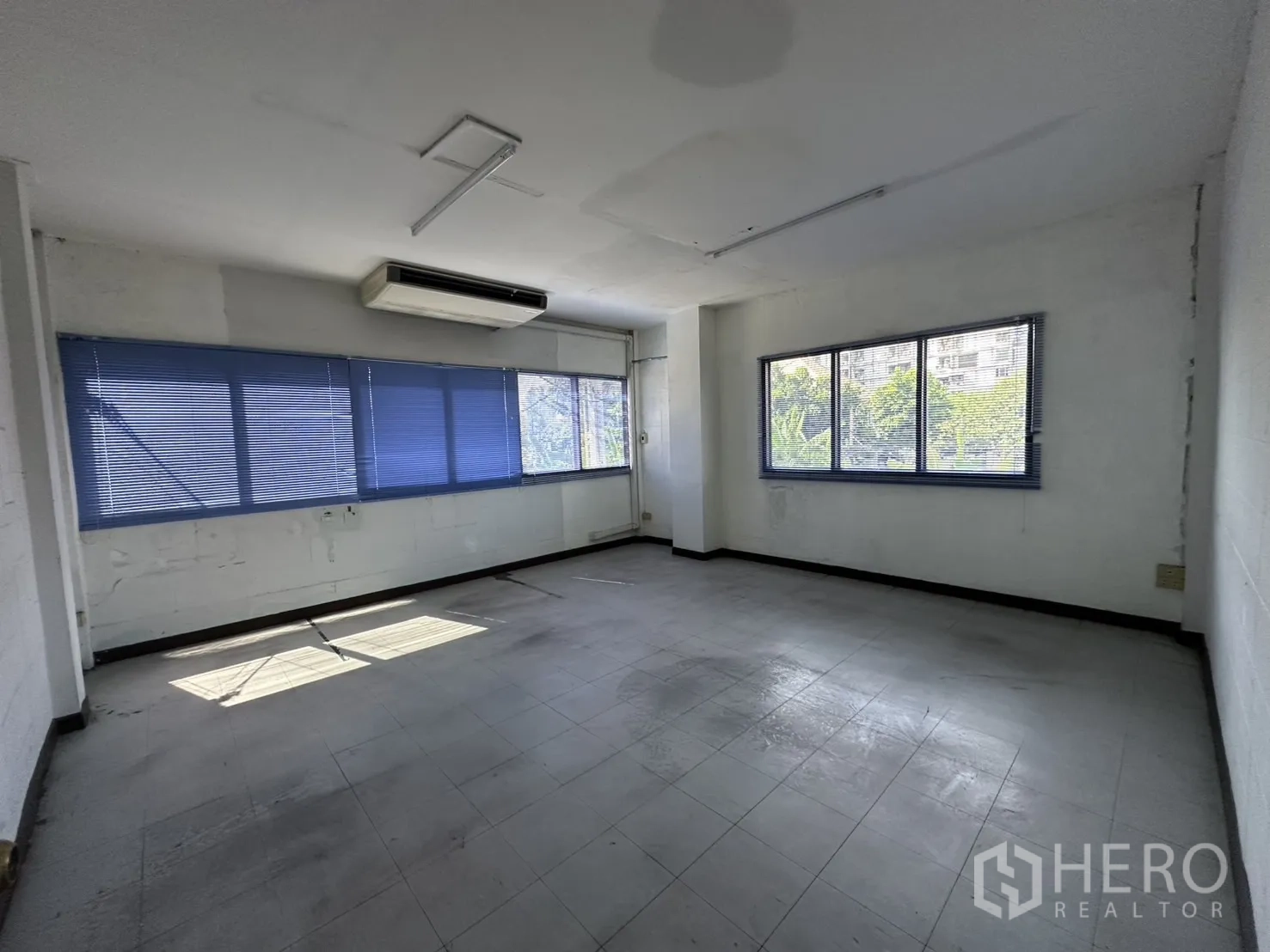 Warehouse for rent in Bang Na, Bangkok - Corner office with wide windows, blue blinds and air conditioner.
