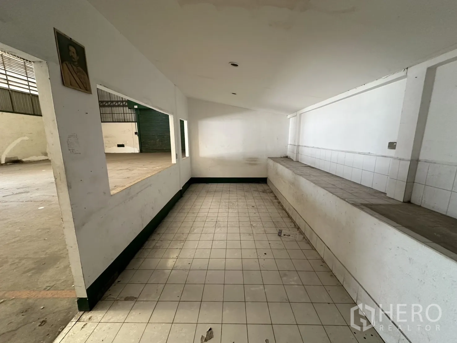 Warehouse for rent in Suan Luang, Bangkok - Long tiled workspace with a raised bench and large wall openings to the main floor.