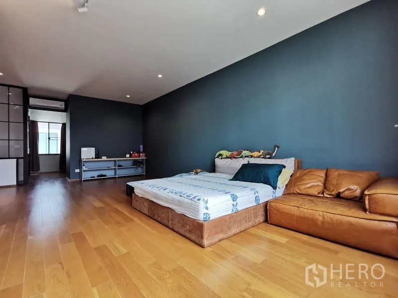 ทาวน์เฮาส์ ขาย - ห้องนอนกว้าง ผนังสีเข้ม เตียงและโซฟาหนังบนพื้นไม้