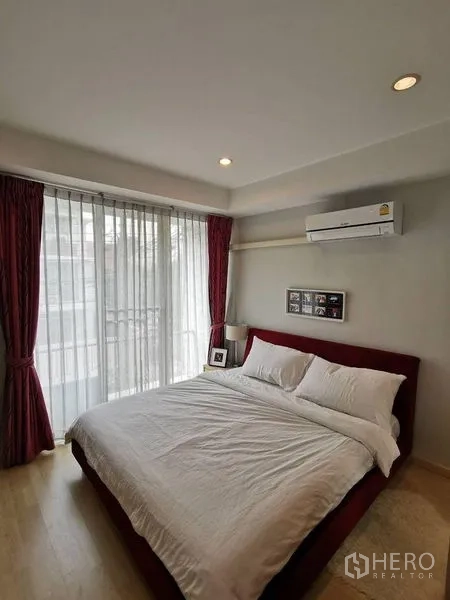 ทาวน์เฮาส์ ให้เช่าหรือขายในYan Nawa, Bangkok - ห้องนอนใหญ่มีหน้าต่างบานกว้าง ผ้าม่านโปร่ง หัวเตียงสีแดง และทางออกสู่ระเบียง