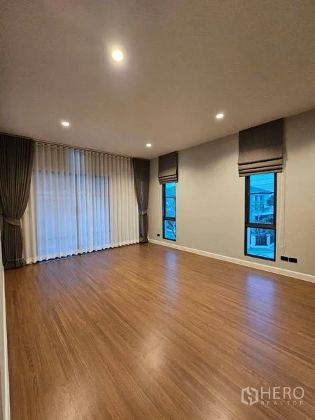 Detached House for rent in Mueang Pathum Thani, Pathum Thani - Spacious upstairs family room with wood floor and full-length curtains