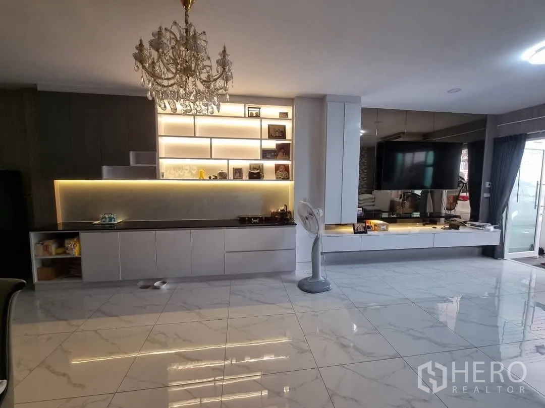 Townhouse for rent in Din Daeng, Bangkok - Open-plan living and dining space with chandelier and illuminated cabinets.