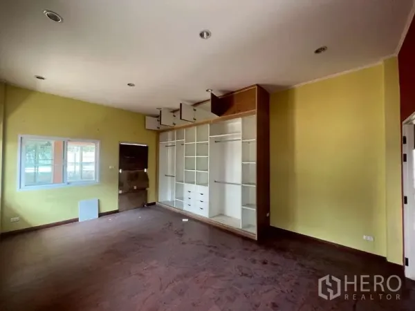 独立式住宅 出租在Watthana, Bangkok - 空房间，木地板，黄色墙面，内置白色柜架。