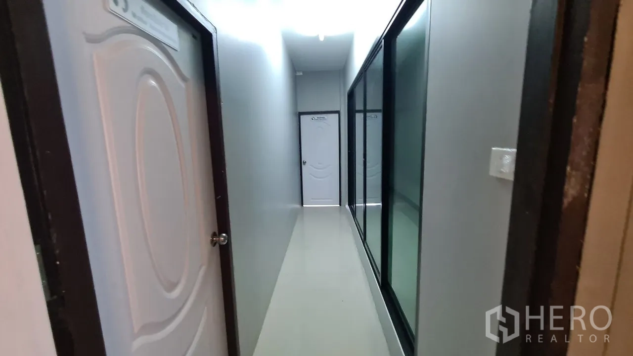Home Office for rent in Pathum Thani - Long corridor with white doors and full-height glass wall partitions.
