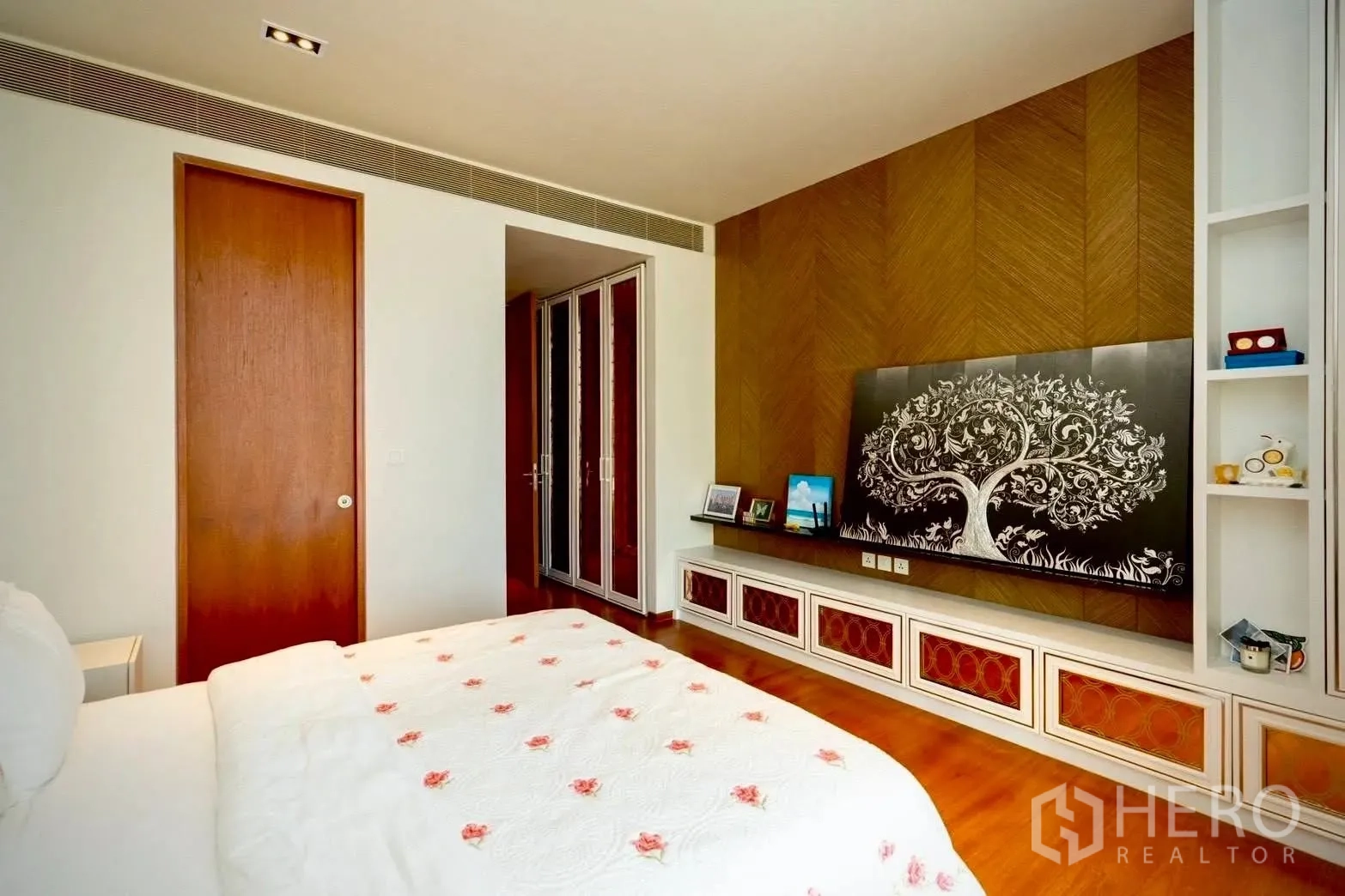Condominium for sale in Sathon, Bangkok - Bedroom with wood accent wall, built-in cabinetry, sliding door, and framed tree artwork.