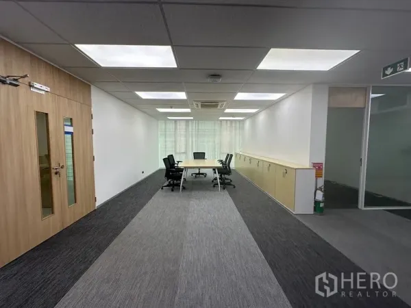 Office Space for rent - Bright Lat Krabang Bangkok office meeting area with long table, carpet tiles, built‑in cabinets and LED panel lighting.