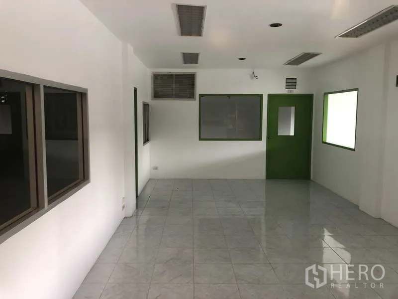 Warehouse for rent in Bang Phli, Samut Prakan - Air-conditioned tiled office room with windows and a green door.