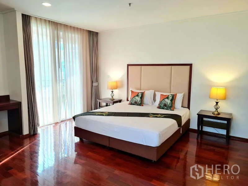 อพาร์ทเมนท์ ให้เช่า - ห้องนอนเตียงคิงพร้อมโต๊ะหัวเตียง และทางออกสู่ระเบียง