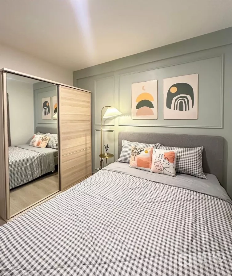 联排别墅 出租在Prawet, Bangkok - 客卧，格纹床品、镜面滑门衣柜和装饰画。