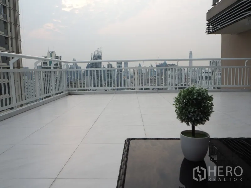 Condominium for rent or sale in Watthana, Bangkok - Expansive private terrace with skyline views and a small potted plant on the table.