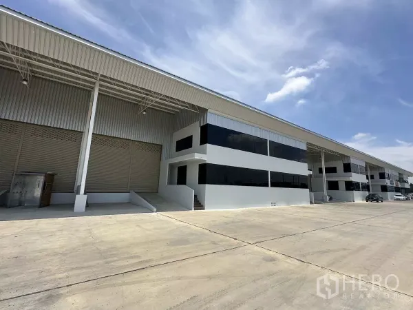 货栈 出租在Wang Noi, Phra Nakhon Si Ayutthaya - 成排仓库，黑框玻璃办公立面与宽敞卡车通道。