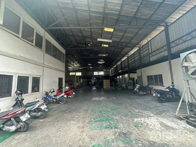 Warehouse for rent in Suan Luang, Bangkok - Central warehouse bay with motorbikes parked and an industrial fan.