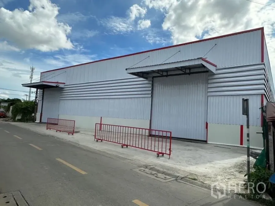 Warehouse for rent in Bang Kapi, Bangkok - Modern metal-clad warehouse exterior with large roller shutter, canopies, and roadside loading area in Bang Kapi.