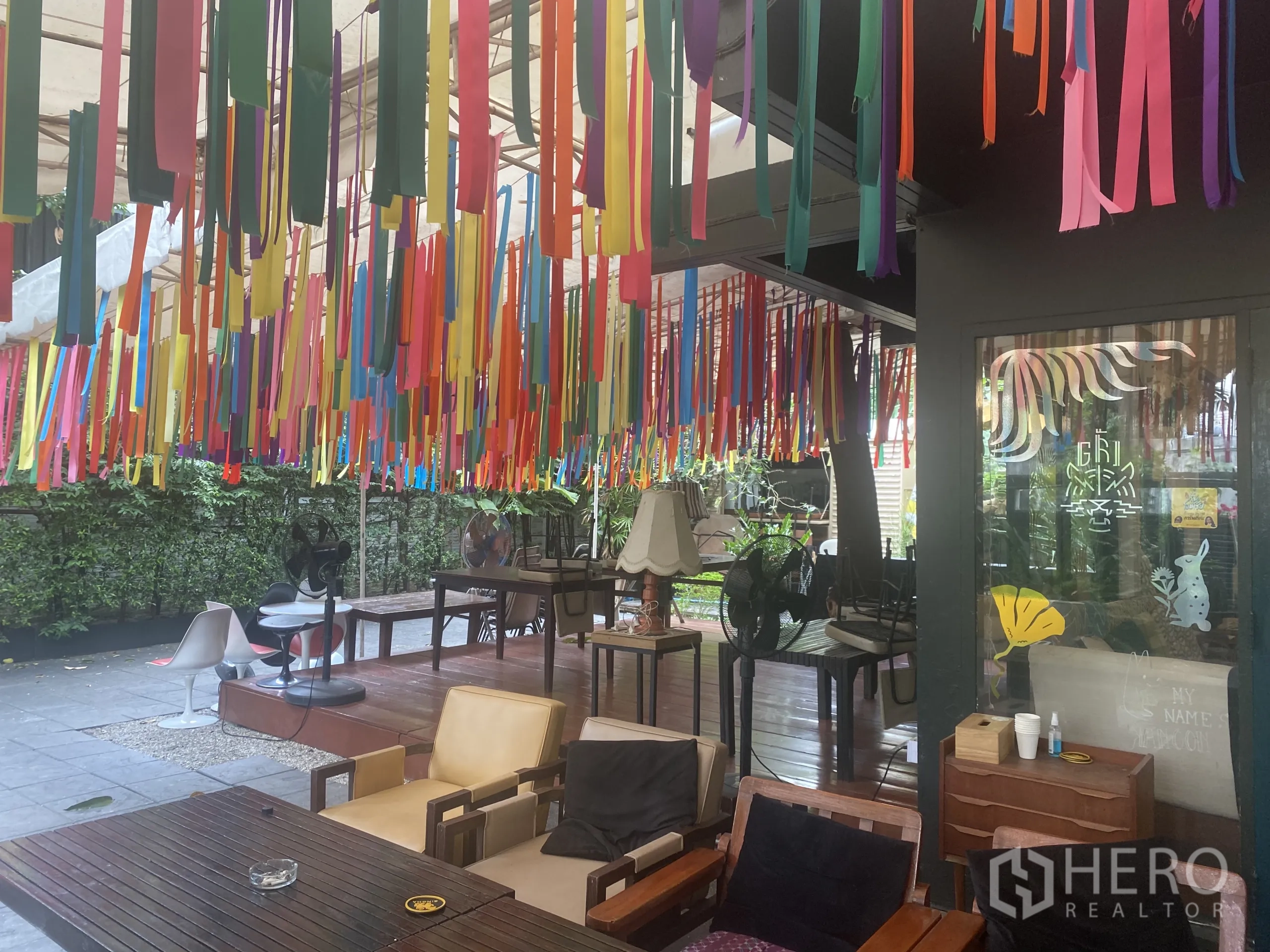 พื้นที่ขายปลีก ให้เช่าในWatthana, Bangkok - ระเบียงมีหลังคาพร้อมริบบิ้นหลากสี โต๊ะไม้ และต้นไม้เขียว