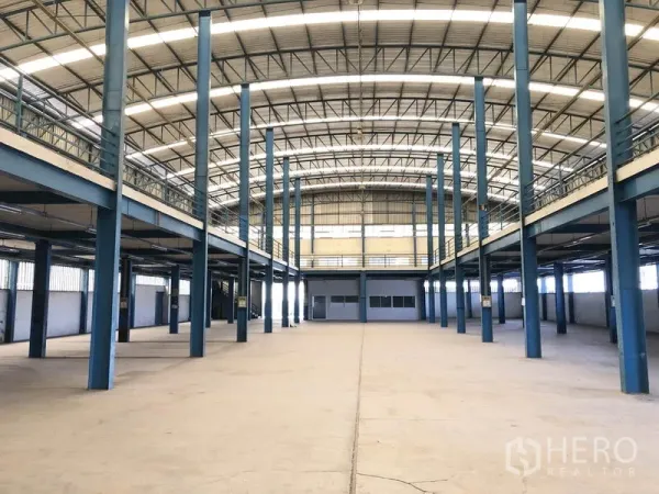 工厂 出租在Sai Noi, Nonthaburi - 高挑拱形屋顶的生产大厅，蓝色钢柱，两侧设夹层