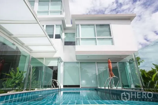 独立式住宅 出租在Lat Phrao, Bangkok - 蓝色瓷砖泳池，配玻璃围栏与落地窗。