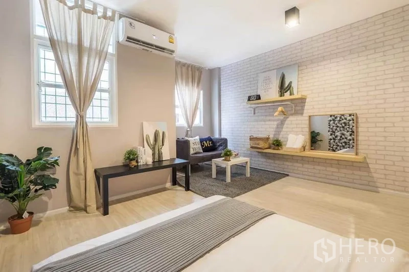 บ้าน ให้เช่าในKhlong Toei, Bangkok - ห้องนอนโทนอบอุ่น ผนังอิฐสีขาว แอร์ โซฟา และชั้นลอย
