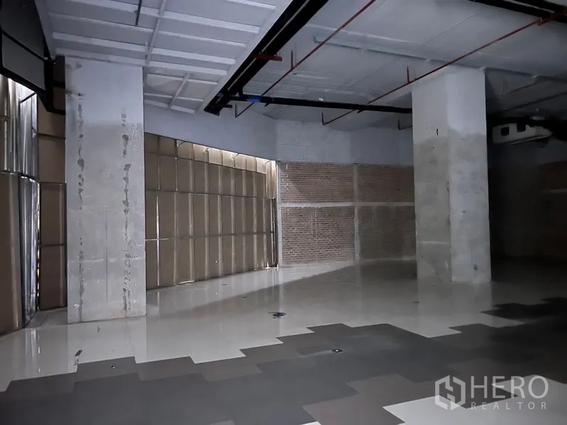 พื้นที่ขายปลีก ให้เช่า - มุมห้องแสดงพื้นกระเบื้องเงา เสาคอนกรีต และงานระบบภายใน