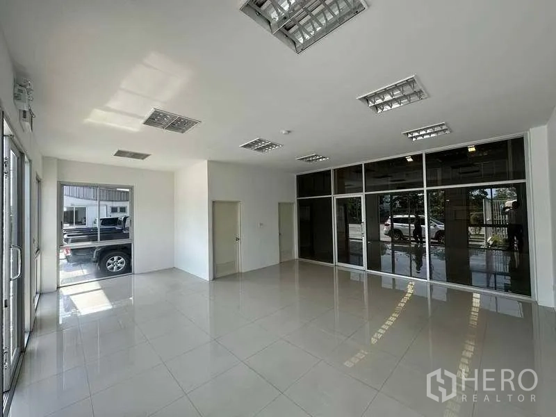Factory for rent in Bang Sao Thong, Samut Prakan - Bright glass-front office or showroom with tiled flooring and multiple ceiling lights.